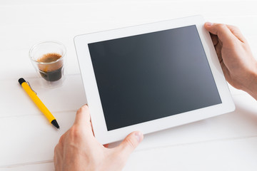 Hands of a man holding blank tablet device over wooden table