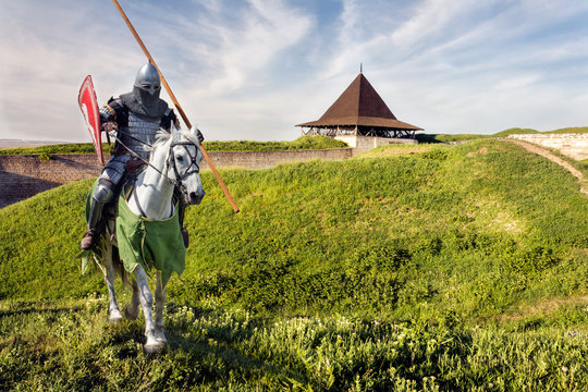 Armored knight on warhorse over old medieval castle