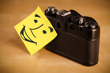 Post-it note with smiley face sticked on a photo camera