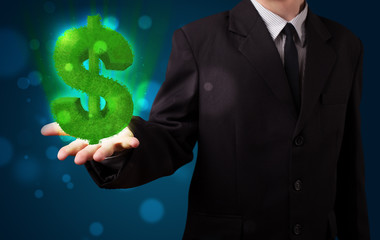 Young businessman presenting green glowing dollar sign