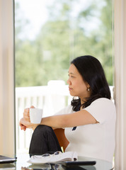 Mature woman relaxing while drinking coffee at home