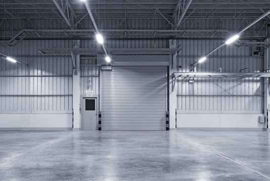 Roller door or roller shutter inside factory, warehouse or industrial building. Modern interior design with polished concrete floor and empty space for product display or industry background.