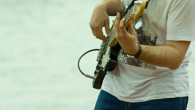 Musician playing guitar on the background of the river