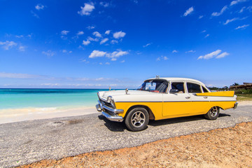 Klasyczna taksówka zaparkowana przy plaży w Vinales na Kubie - 66583471