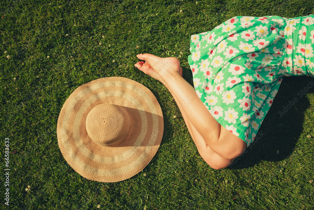 Wall mural young woman with hat sleeping in the park