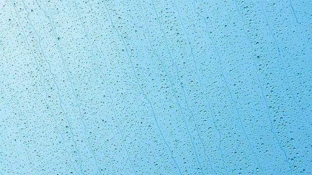 Raindrops on glass run against the blue sky