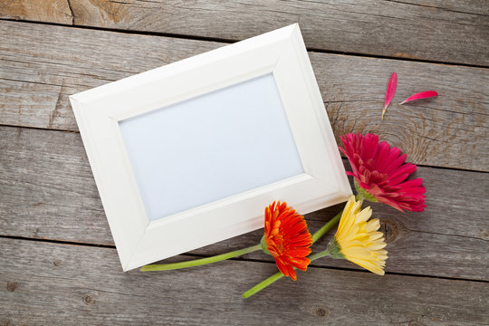 Three colorful gerbera flowers and photo frame
