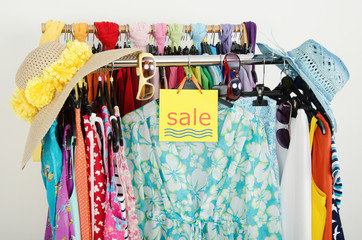 Clearance rack with colorful summer clothes and sale sign.