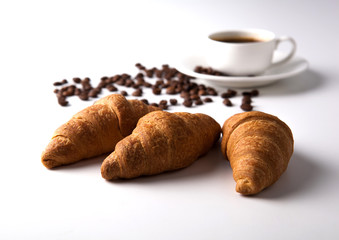 three croissant and a cup of coffee with coffee beans