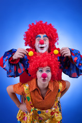 Two happy clowns playing on blue background