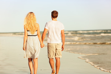 Beach couple holding hands walking at sunset