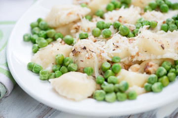Close-up of square ravioli with green peas, nuts and parmesan