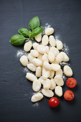 Italian gnocchi with green basil and tomatoes, view from above