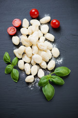 Gnocchi with tomatoes and basil over black wooden background