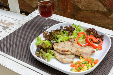 Grilled pork on white plate with glass of wine