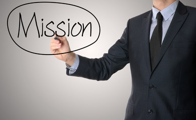 business man writing mission concept on grey background