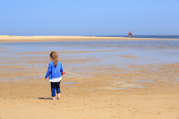 Young girl walking on a sandy beach