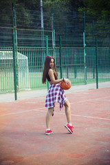 Beautiful young woman playing basketball outdoors