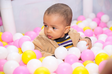 Fototapeta na wymiar Happy black boy in colored ball on birthday on playground