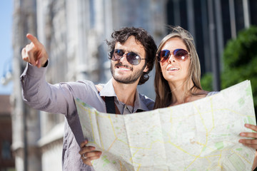 Happy tourists couple holding map - Powered by Adobe