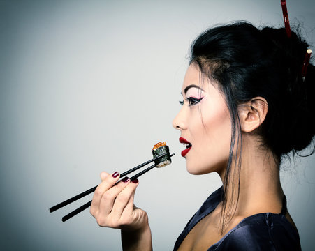 Young Beautiful Asian Woman Eating Sushi With Chopsticks, Toned