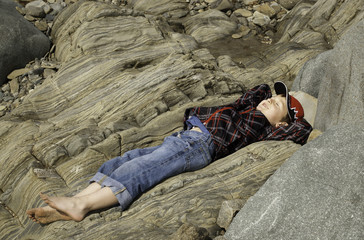 Boy Lying on Rock on the Beach
