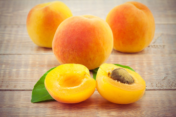 Fototapeta na wymiar Ripe peaches with leaves on wooden table