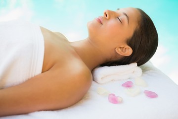 Obraz na płótnie Canvas Calm brunette lying on towel with rose petals