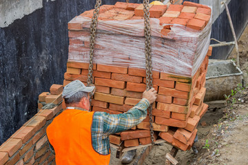 Construction crane delivered clay brick on pallet