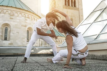 Crédence de cuisine en verre imprimé Arts martiaux Jeunes partenaires de capoeira effectuant des coups de pied en plein air