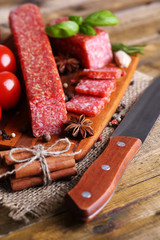 Tasty salami sausage and spices on wooden background