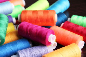Multicolor sewing threads on wooden background