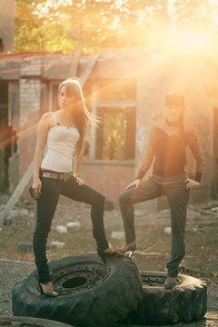 Full body shot of a two women standing on a tyres outdoors