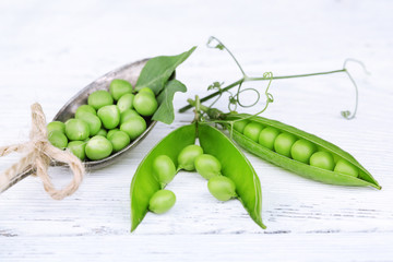 Fresh green peas in spoon on wooden table