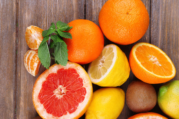 Fresh citrus fruits with green leaves on color wooden