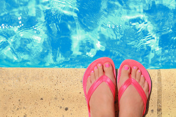 Female feet with flip flops by the pool