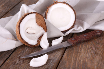 Broken coconut with knife and napkin on wooden background
