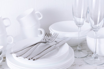 Set of white dishes on table on light background