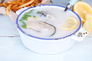 Tasty soup with oysters on wooden table