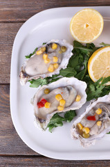 Tasty cooked oysters in shell on wooden table