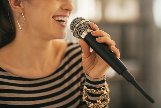 Closeup on happy young woman singing with microphone