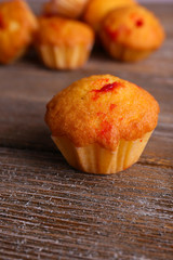 Tasty muffins with red currant on wooden background