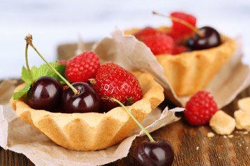 Tasty tartlets with berries on wooden table