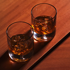 Highball whiskey glass with ice on wooden background.