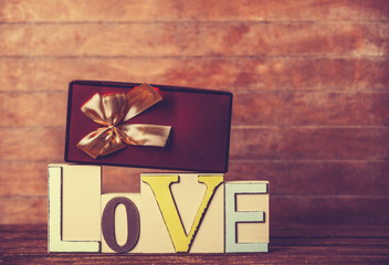 Little gift and word Love on wooden table.