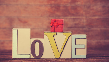 Little gift and word Love on wooden table.