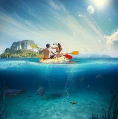 Man and girl kayaking next to a tropical island