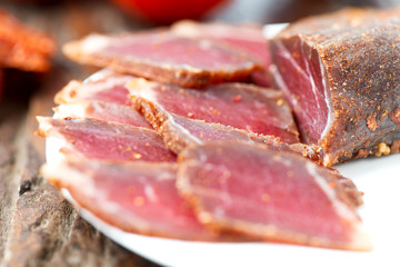 Slices of cured meet on plate close up