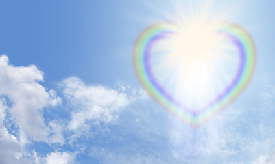 Heart rainbow bursting with light on a blue sky