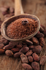 grated dark chocolate in old wooden spoon on roasted cocoa choco
